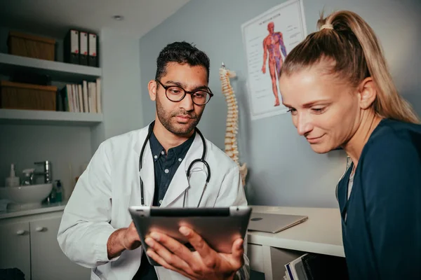 Gemengde ras vrouwelijke verpleegkundige zitten met mannelijke arts met behulp van digitale tablet — Stockfoto