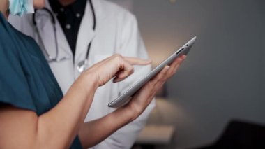 Doktorlar ofiste dikilip dijital aygıtla o günün programını kontrol ediyorlar.
