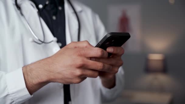 Primo piano medico di sesso maschile digitando sul dispositivo cellulare — Video Stock