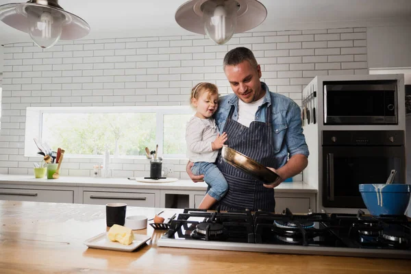 Pai e filha assar muffins na cozinha segurando panela quente. — Fotografia de Stock