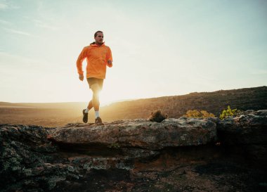 Ufuktaki güzel günbatımında yürüyüş yaparken dağda koşan beyaz erkek sporcu.