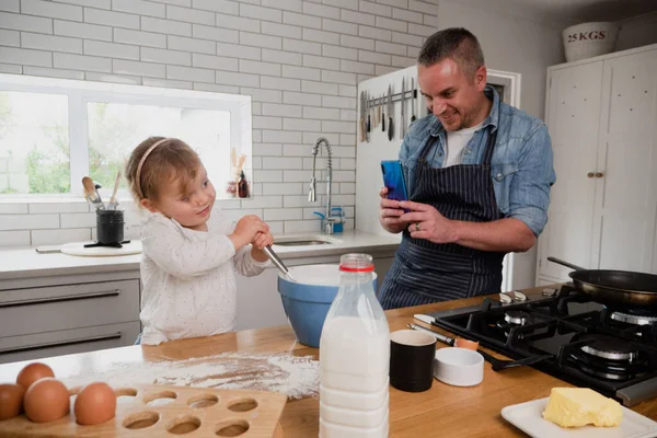 Pai caucasiano tirando foto de filha assando na cozinha — Fotografia de Stock