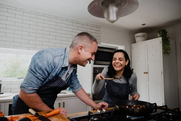Casal se divertindo, rindo na cozinha e cozinhando juntos — Fotografia de Stock