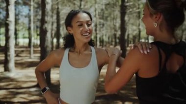 Karışık ırk bayan arkadaşları uzun koşudan önce ormanda kollarını ve omuzlarını esnetiyorlar.