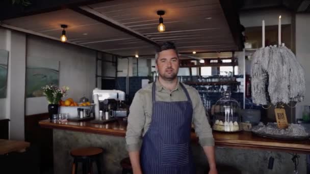 Przystojny kelner stojący z krzyżem uzbrojony w funky cafe. — Wideo stockowe