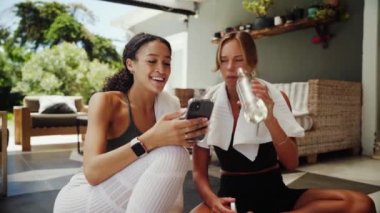 Karışık ırk arkadaşları, dışarıda egzersiz yapıyor. Hücresel cihaz üzerinde kayıyor. Etkinlik kayıtlarını kontrol ediyor. 