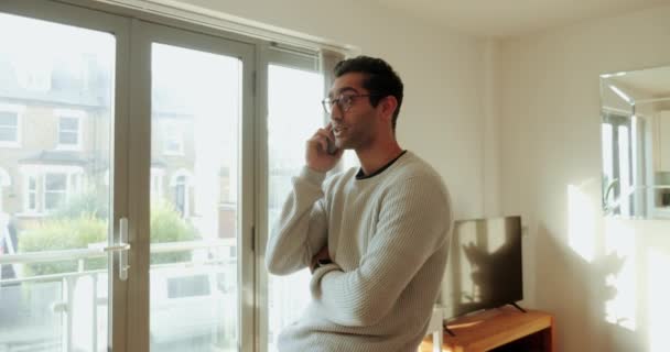 Carrera mixta hombre de negocios charlando en el dispositivo celular caminando por la sala de estar — Vídeo de stock