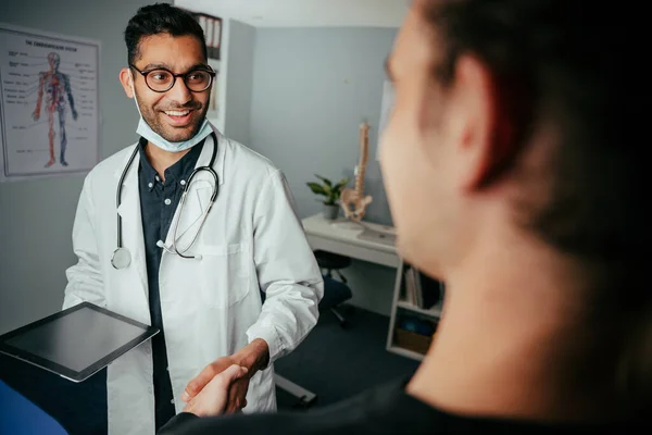 Gemengde ras mannelijke verpleegkundige chatten met patiënt in kliniek — Stockfoto