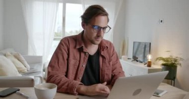 Uzayda düşünürken gülümseyerek evde çalışan beyaz erkek öğrenci.