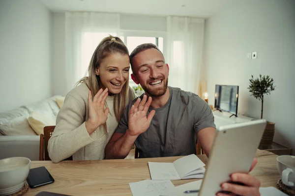 Kaukázusi pár ül a konyhaasztalnál integetett a kamera, miközben videohívás a családdal — Stock Fotó