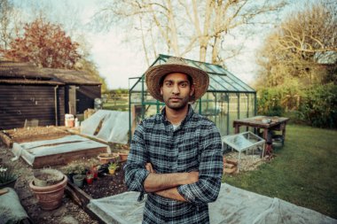 Yeşil evin yanında duran melez erkek çiftçi. 