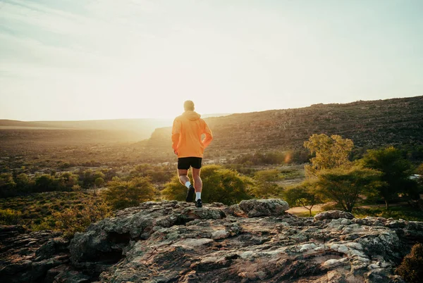 Caucasian male athlete having a break from outdoor run hiking reaching mountain peak watching beautiful sunset — Stock Photo, Image