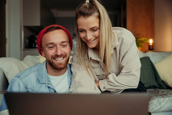 Kaukázusi pár ül kanapén mosolyogva, miközben videohívás segítségével laptop — Stock Fotó