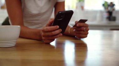 Beyaz kadın mutfakta elinde cep telefonu cihazıyla online ödeme yapıyor. 