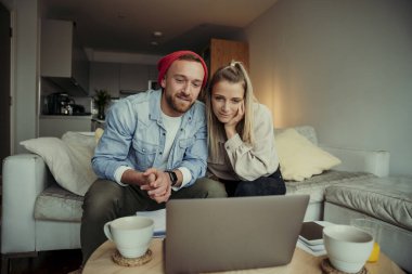 Kafkasyalı mutlu çift kanepede oturmuş aileleriyle görüntülü konuşma yapıyorlar.