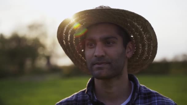 Close up mestiço agricultor masculino vestindo chapéu de palha em pé em campos de trigo — Vídeo de Stock