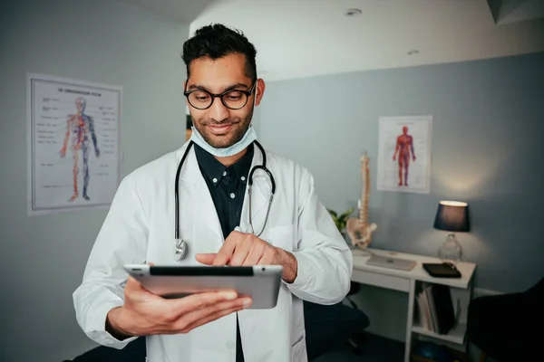 Infirmière masculine mixte souriante portant un équipement chirurgical debout dans une clinique tenant une tablette numérique — Photo