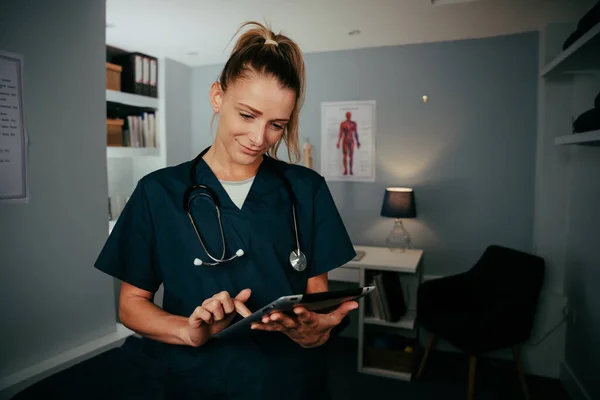 Blanke vrouwelijke arts werkzaam in kliniek typen op digitale tablet — Stockfoto