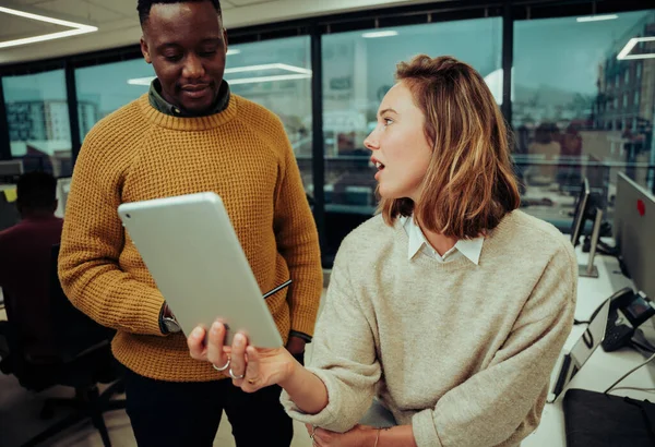 Designer donna caucasica non impressionato con i disegni realizzati da partner maschile in cerca di tablet digitale seduto in ufficio — Foto Stock