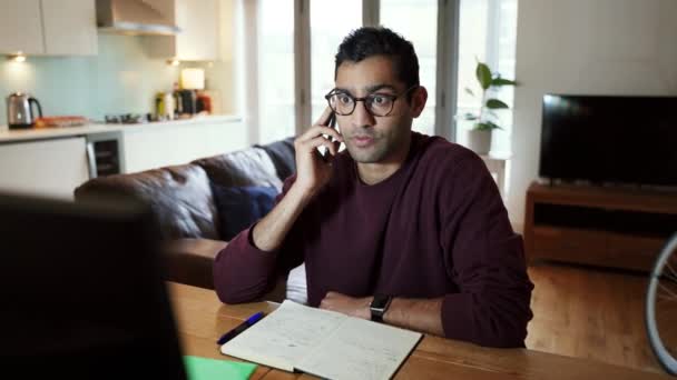 Mixte homme d'affaires course bavarder sur l'appareil cellulaire de travail à partir de la saisie de bureau à domicile sur ordinateur portable — Video