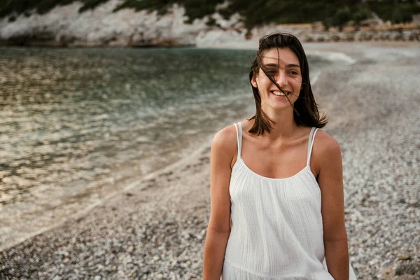 Beyaz kadın kumsalda gülümsüyor.