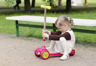 küçük kız bir kaykay üzerinde oturuyor