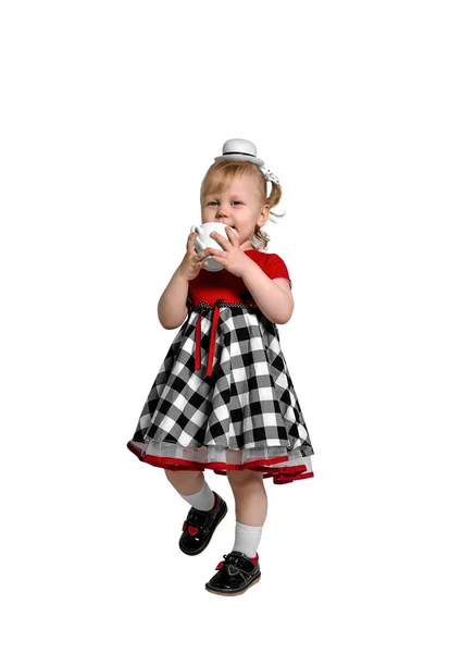 Little girl in hat drinking from a white cup — Stock Photo, Image
