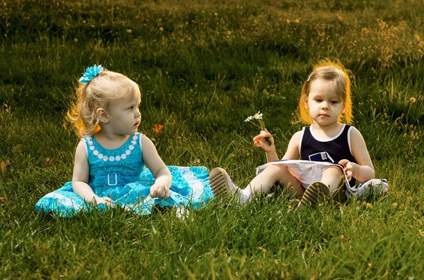 Deux petites sœurs assises dans l'herbe Image En Vente