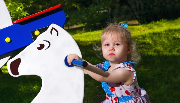 Bambina che cavalca su un'altalena sotto forma di cavallo — Foto Stock