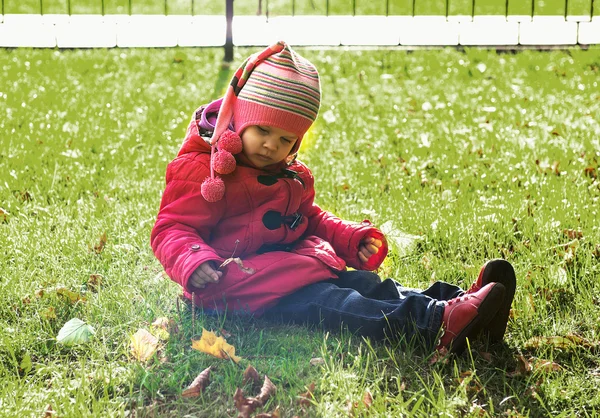 Petite fille en veste rouge assise sur le sol — Photo