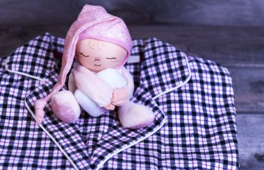 Pazen pijama ve yumuşak oyuncak bebek üzerinde ahşap masa kareli 