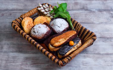 On a light wooden table with  tray of eclairs