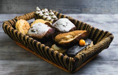 On a light wooden table with tray of eclairs