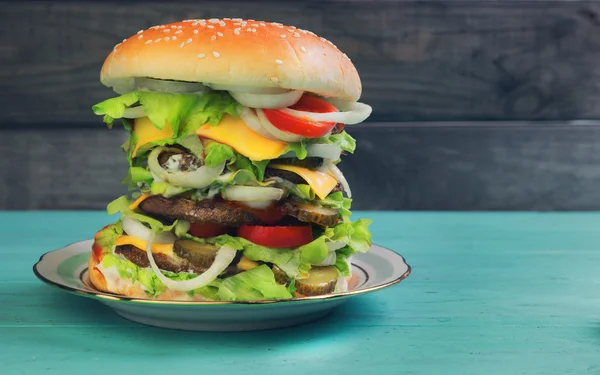 Big cheeseburger deluxe high on green wooden background — Zdjęcie stockowe