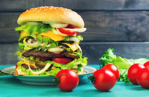 Big cheeseburger deluxe high on green wooden background — Stockfoto