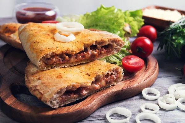 Zamknięte pizza calzone na jasnym tle drewniane — Zdjęcie stockowe