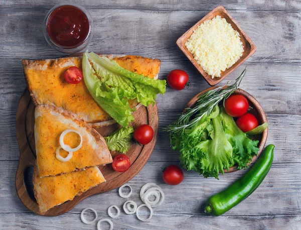 Geschlossene Pizzazone auf hellem Holzgrund — Stockfoto