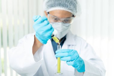 Araştırmacı ya da bilim adamları laboratuardaki test tüpüne sıvı örneği yüklüyorlar. Araştırmacılar COVID-19 virüsünü tedavi etmek için aşı ve ilaç geliştiriyorlar..