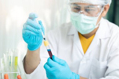 Araştırmacı ya da bilim adamları test tüpündeki kan örneğine sıvı yükler. Araştırmacılar COVID-19 virüsünü tedavi etmek için aşı ve ilaç geliştiriyorlar..