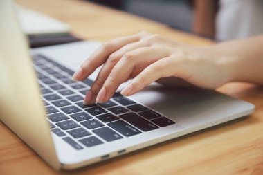 İş kadını ellerinin ofis masasında dizüstü bilgisayara yakın durması. İnternette veya internette arama yapmak için dizüstü bilgisayar kullanan kadın, ev ofisi kavramı.