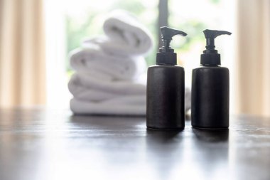 Şampuan şişeleri, sıvı sabun şişeleri ve masadaki beyaz havluların üzerinde bulanık oda arka planında fotokopi alanı var. Ürün görüntüleme kurgusu için.