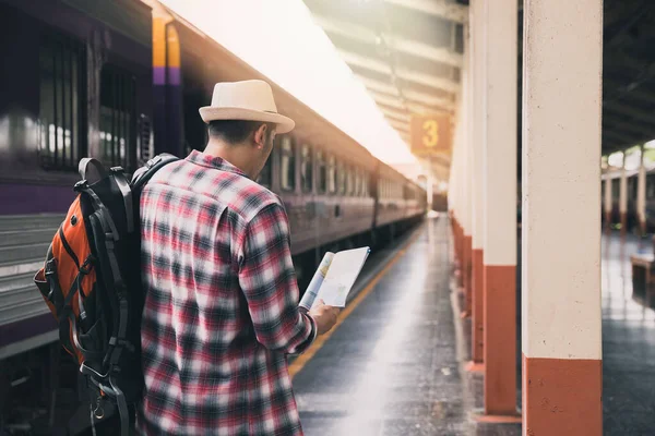 A man using map to travel at train station. Travel concept.