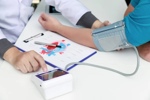 Hastanedeki hastanın kan basıncını ölçen doktor, tıbbi ve sağlık konseptleri.