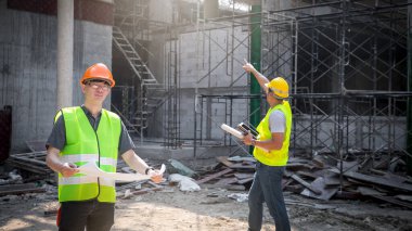 Mimar, Mühendis, Müteahhit ya da İnşaat Yöneticisi bir inşaat sahasında bir grupla birlikte projeyi tutuyor..