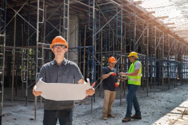 Mimar, Mühendis, Müteahhit ya da İnşaat Yöneticisi bir inşaat sahasında bir grupla birlikte projeyi tutuyor..