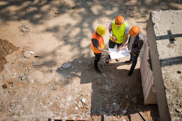 建設現場のエグゼクティブ スーパーバイザとプロジェクトの詳細を議論する建設労働者のチーム — ストック写真