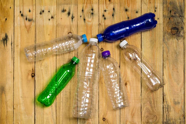 Used plastic bottles on wooden board — Stock Photo, Image