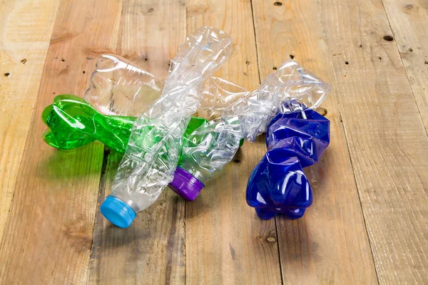 Used plastic bottles on wooden board — Stock Photo, Image