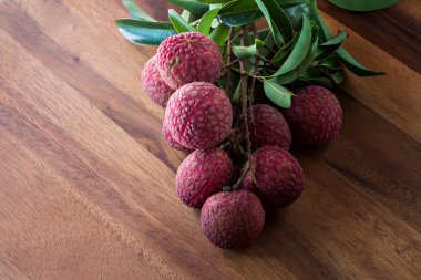 Lychee ile ahşap bir masa, Natürmort yapraklarda