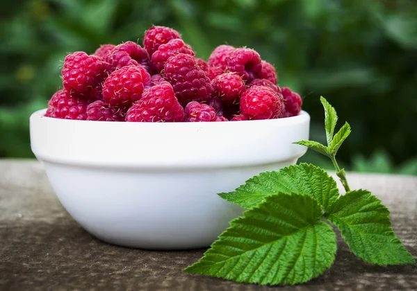 White plate full of fresh berries ripe raspberry is on the table — Stock Photo, Image